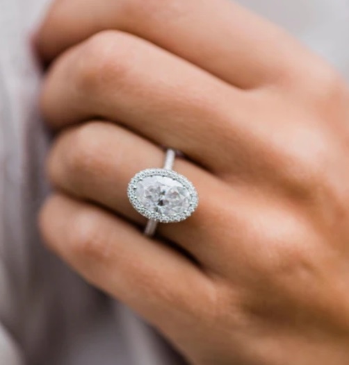 Oval halo moissanite engagement ring shown on hand