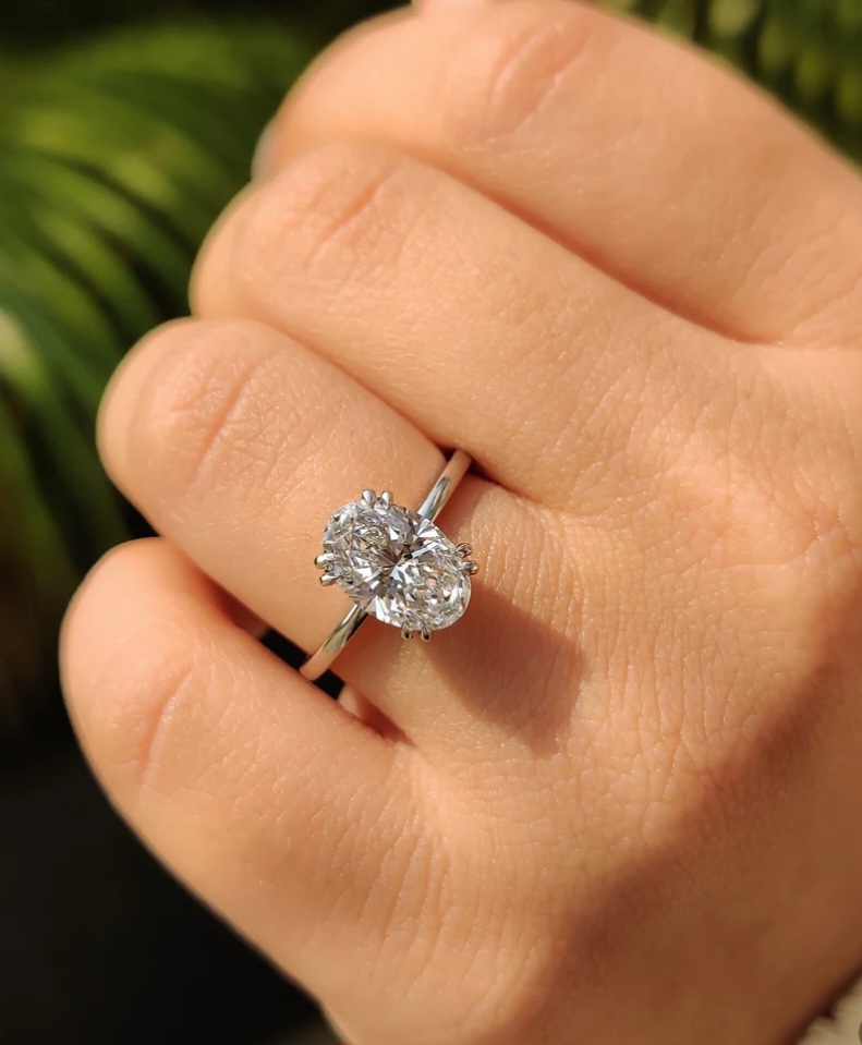 Oval solitaire moissanite engagement ring shown on hand